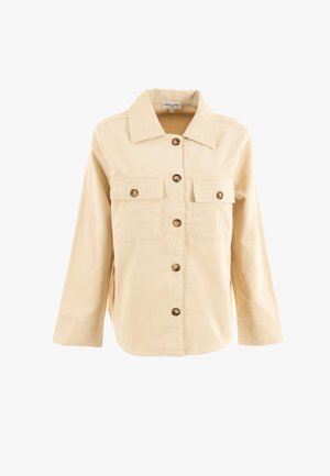 Beige corduroy overhemdjack met een puntige kraag, lange mouwen en een knoopsluiting aan de voorkant. Heeft twee borstzakken en bruine knopen.