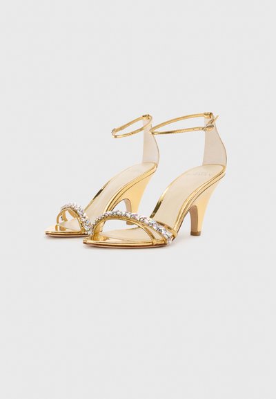 Sandali con tacco alto color oro con cinturino trasparente, decorati con strass scintillanti sul cinturino delle dita, caratterizzati da un design elegante.