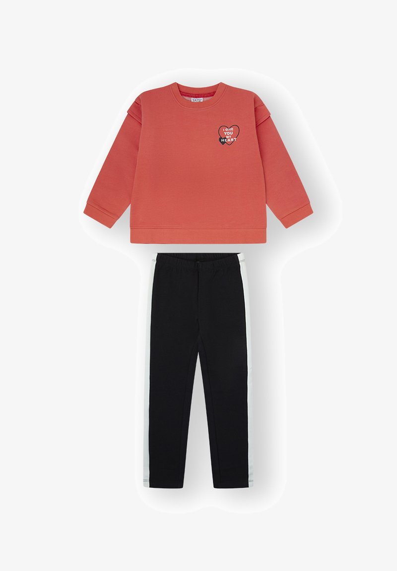 Sudadera coral de manga larga con gráfico de corazón y texto "Te doy mi corazón", combinada con pantalones negros con franjas blancas laterales.