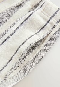 Beiger Stoff mit dunkelblauen Streifen, ausgestattet mit einer strukturierten Webweise. Die Kanten sind ordentlich genäht, was das strukturierte Design betont.