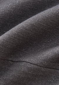 Tessuto grigio texture con una fine trama e un delicato luccichio, con pieghe morbide che evidenziano la leggerezza del materiale.