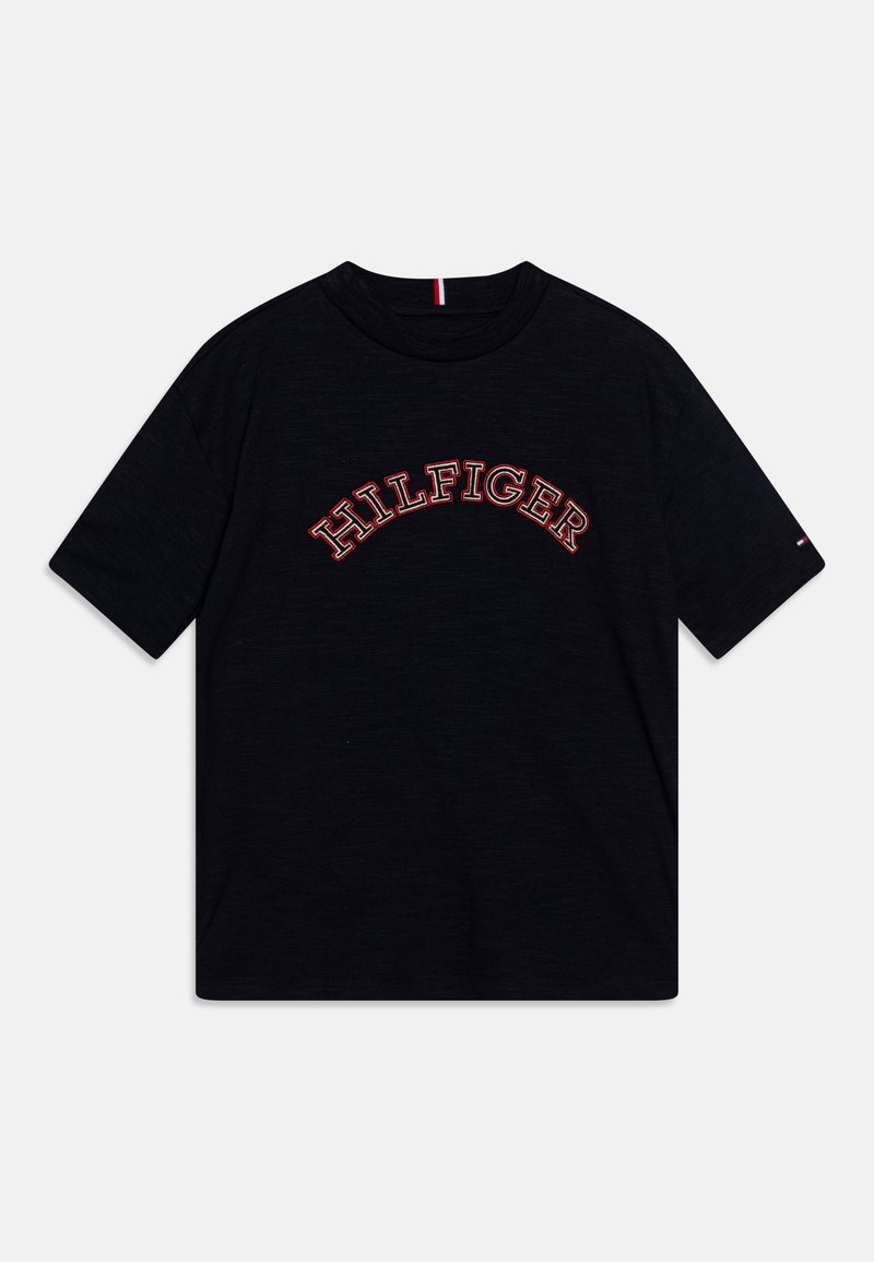 Camiseta negra de algodón, con un logo bordado en rojo de "HILFIGER" en diseño de arco en la parte frontal. Mangas cortas, cuello redondo.