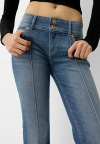 Blaue Jeans mit hoher Taille, zwei-Knopf-Verschluss und dezenten Nähten. Enganliegendes Design mit Fronttaschen.