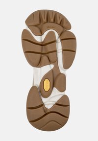 Sole boty s podešví Vibram v světle hnědé a bílé barvě. Obsahuje různé textury, drážky a zlatý akcent loga pro trakci a odolnost.