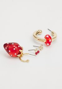 Red strawberry-shaped earrings with white polka dots, gold hoop accent, and two smaller stud earrings in red and gold tones.