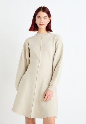 Beige knitted dress with a high neckline, long sleeves, and a straight cut. Features a central seam and ribbed cuffs. Soft texture.