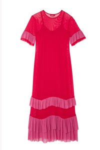 Genomskinlig klänning i starkt rosa med korta volangärmar, lagerdesign och rosa volanger i fållen. Slät textur och flödande silhuett.