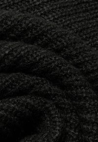 Μαύρο παχύ πλεκτό ύφασμα με απαλή, υφασματική επιφάνεια και μοτίβο από αλληλένδετους βρόχους και ίνες.