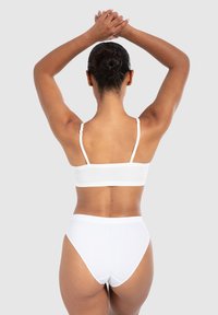 Witte geribde bralette en hoog opgesneden slips. Zachte stof, dunne verstelbare bandjes en naadloos ontwerp. Eenvoudige, strakke lijnen verbeteren de pasvorm.