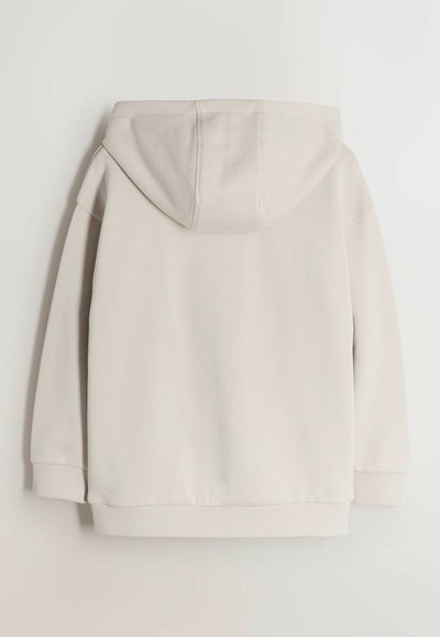 Sweat à capuche beige à manches longues, avec poignets et ourlet côtelés, présenté de dos sur un fond uni.