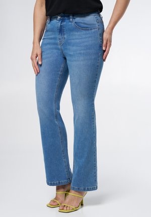 Lichtblauwe denim flared jeans met een gemiddelde taillehoogte, vijf zakken en een gladde textuur. Gepaard met groene hakken met bandjes.