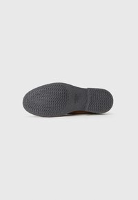 Gray rubber shoe sole with textured surface, featuring a slight curve at the toe and heel. Minimal branding visible near the center.