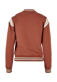 Punakasoranž džempripluus soonikkoelusega krae ja mansettidega. Valged õlaaktsendid, triibuline serv ja sile tekstuur. Tagantvaade.