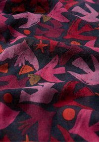 Multicolored stof met een patroon van vogels en geometrische vormen in rood, roze en oranje op een donkere marineblauwe achtergrond. Zachte textuur.