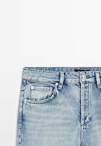 Vaaleansiniset farkut suoran leikkauksen kanssa. Ominaisuuksiin kuuluvat nappi ja vetoketju, etutaskut sekä huomaamattomat ompeluyksityiskohdat.