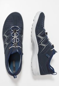 Scarpe sportive blu scuro con pannelli in rete, accenti riflettenti e suola in gomma grigia. Caratterizzano un design con lacci e chiusura a toggle.