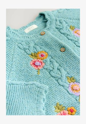 Dziewińszy kardigan w jasnoniebieskim kolorze z teksturowanym wzorem. Ozdobiony różowym, żółtym i fioletowym haftem kwiatowym oraz brązowymi drewnianymi guzikami.
