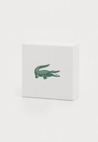 White box with a textured surface featuring a green crocodile graphic. The crocodile design includes distinctive triangular patterns.