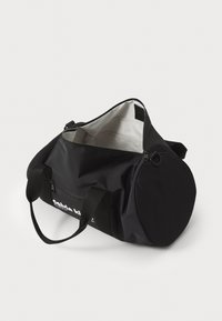 Black duffel bag made of durable fabric, featuring a zippered opening, two sturdy handles, and a rounded side for ample storage space.
