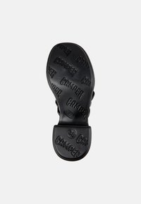 Black rubber shoe sole featuring embossed "CAMPPER" branding, round heel, and size "38" detail, with a textured surface for grip.