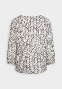 Langermet bluse laget av lett stoff, med grå bakgrunn og hvitt bladmønster samt elastiske mansjetter. Rund halsutskjæring.