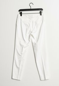 Vita skräddarsydda byxor med en slät yta, med medelhög midja, bakfickor och en skräddarsydd silhuett, hänger på en svart galge.