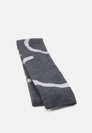 Écharpe pliée gris foncé avec des lignes abstraites blanches courbées sur un fond clair uni.