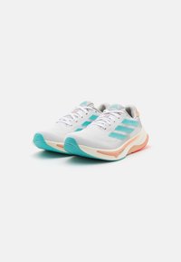 Bílé sportovní boty s tyrkysovými akcenty, strukturovaným síťovaným svrškem a lehkou podrážkou s broskvovými detaily.