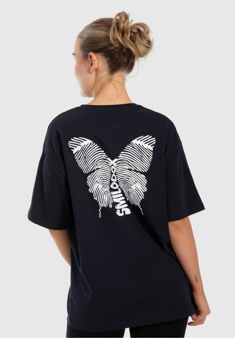 Marineblaues, übergroßes T-Shirt mit einem weißen Schmetterlingsdesign aus Fingerabdruckmustern. Mit kurzen Ärmeln und entspannter Passform.