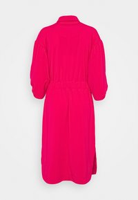 Robe rose vif longueur genou avec longues manches bouffantes, un col, taille froncée et une fente latérale, vue de dos sur un fond uni.
