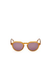 Gafas de sol marrones y redondas con acabado mate; lentes morados; patillas elegantes con sutiles acentos de marca.