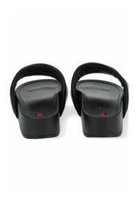 Chanclas negras con plantilla acolchada. Presentan dos correas anchas y un tacón bajo. El diseño se centra en la comodidad y el minimalismo.