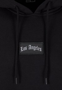 Felpa nera con cappuccio e cordino, caratterizzata da una toppa rettangolare con la scritta "Los Angeles" in carattere gotico bianco. Tessuto morbido, design casual.