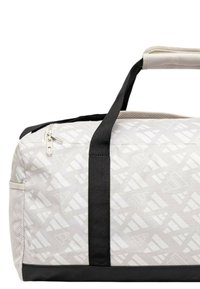 Borsa da viaggio grigio chiaro con motivo geometrico bianco; base e manici neri, chiusura zip in cima, tasca laterale in rete per aerazione.