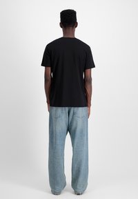 Must have lühikeste varrukatega must T-särk, millel on mugav lõige, koos helesiniste laiade pükstega, millel on kaks tagataskut ja narmendav ääreosa.