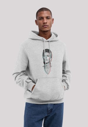 Grauer Kapuzenpullover mit einer Fronttasche und Kordelzugkapuze. Mit einem stilisierten Grafik eines Gesichts in kontrastierenden Farben. Weiche Textur.