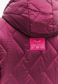 Prošívaná bunda s kapucí ve tmavě vínové barvě, zdobená velkým vzorem kosočtverců a růžovou nášivkou s textem a grafickým motivem na zádech.