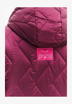 Pikowana kurtka z kapturem w głębokim burgundzie, z dużym wzorem diamentowym oraz różową metką z tekstem i grafiką na plecach.
