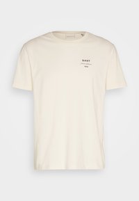 T-shirt blanc cassé à manches courtes et col rond avec petit texte noir « GANT Premium Sportswear 1949 » sur le côté gauche de la poitrine.