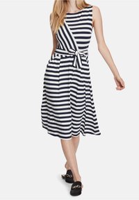 Navy and white striped sleeveless dress with a tied waist and flowing skirt. Crafted from soft fabric, featuring side pockets and a round neckline.