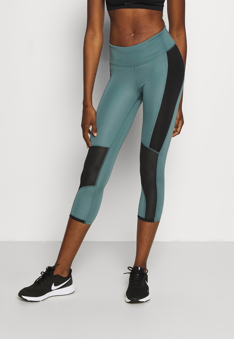 Tealové a černé capri legíny mají vysoký pas, kontrastní panely a hladkou strukturu, vhodné pro sportování.