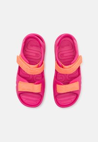 Pink rubber sandals with two adjustable orange straps, textured footbed, contoured shape, and flexible sole, size 28.