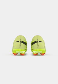 Egy pár sárga Nike Mercurial futball cipő fekete swoosh-al és piros stoplival, hátulról nézve, fehér háttér előtt.