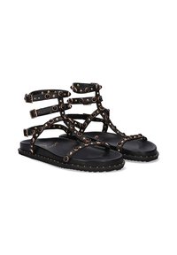 Sandalias gladiadoras negras con múltiples correas, adornadas con tachuelas redondas y una suela de goma plana. Presenta hebillas para un ajuste ajustable.