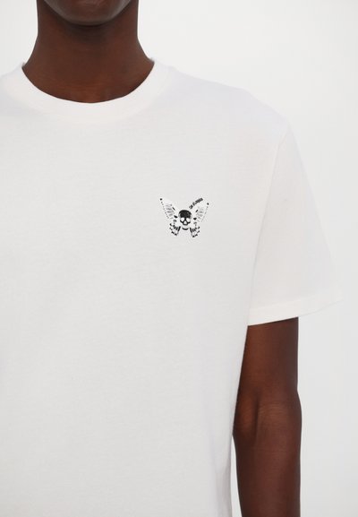 White cotton t-shirt featuring a black butterfly graphic with a skull at the center, displayed on the upper left chest area.