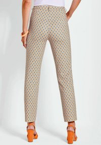Pantaloni con motivo su sfondo arancione chiaro, caratterizzati da una stampa a diamante blu; design a gamba dritta con una texture liscia e tasche posteriori.