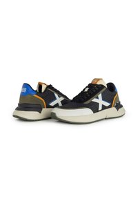 Sneaker in rete nere con accenti blu e arancioni, logo bianco e suola chunky grigia. Parte superiore testurizzata con dettagli a contrasto sulla punta e sul tallone.