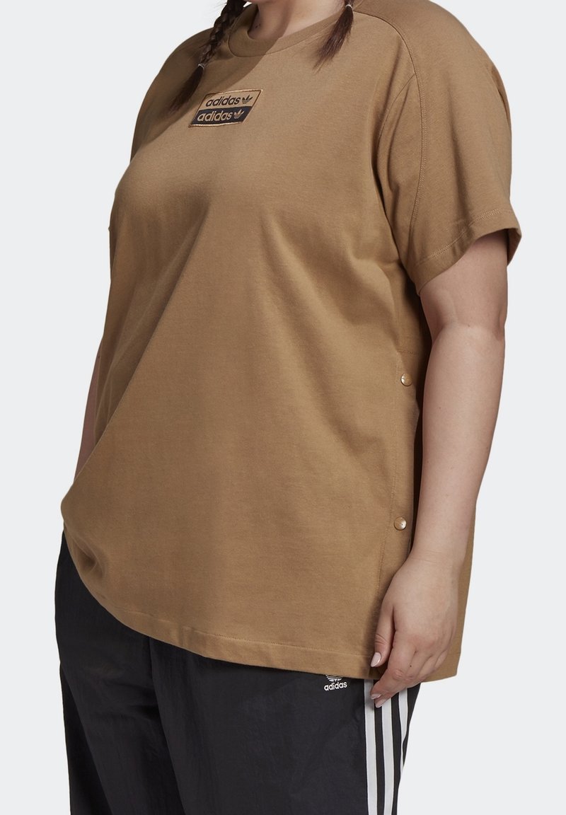 Bruine, korte mouwen t-shirt van katoen met een oversized ontwerp. Bevat een merkpatch en drukknopenaccenten aan de zoom.