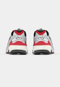 Αθλητικά παπούτσια με ανοιχτό δίκτυ κορυφή σε ασημί, μαύρες λεπτομέρειες και κόκκινες λεπτομέρειες στη φτέρνα. Παχύ λευκό πέλμα με μαύρη επιφάνεια για καλύτερη πρόσφυση.