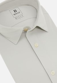Camisa gris claro de botones con un cuello clásico, que presenta dos botones crema y una textura suave. La etiqueta dice "BOGGI MILANO BTECH L."